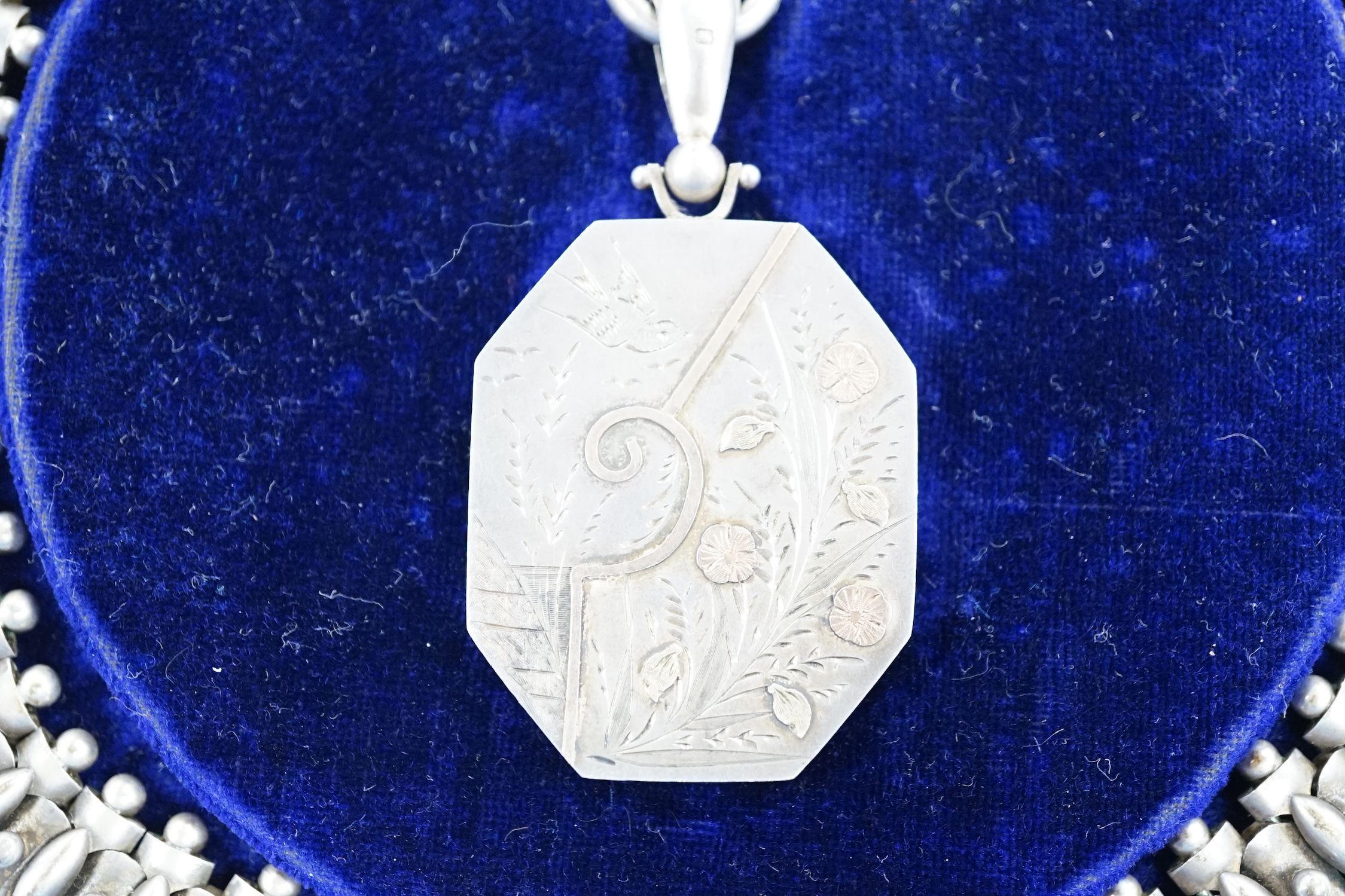 A Victorian silver octagonal locket with engraved aesthetic decoration, Birmingham, 1881, 43mm, on a white metal Etruscan revival chain, 42cm, in fitted case.